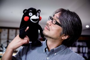 Tokyo, June 9 2014 - Portrait of Japanese author, screenwriter and radio personality Kundo KOYAMA at his office in the Toranomon area. Mr KOYAMA hold the mascot of Kumamoto prefecture, Kumamon. He was charged with promoting the prefecture when a new bullet train service linking Kumamoto with the commercial hub of Osaka was being launched. Mr Koyama then asked art director Manabu Mizuno to create a campaign logo, and threw in the cuddly Kumamon as a bonus.